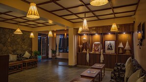 A spacious lobby with a stone wall, wooden furniture, and hanging lamps. - Hotel 100 Petals - Gangtok 12 mins from MG Marg (Gangtok)