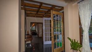 A hallway with a wooden door, a potted plant, and a small table. - Hotel 100 Petals - Gangtok 12 mins from MG Marg (Gangtok)
