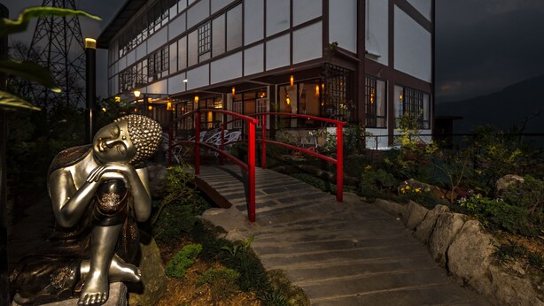 A traditional building with a red staircase leading to a wooden deck, surrounded by greenery. - Hotel 100 Petals - Gangtok 12 mins from MG Marg (Gangtok)
