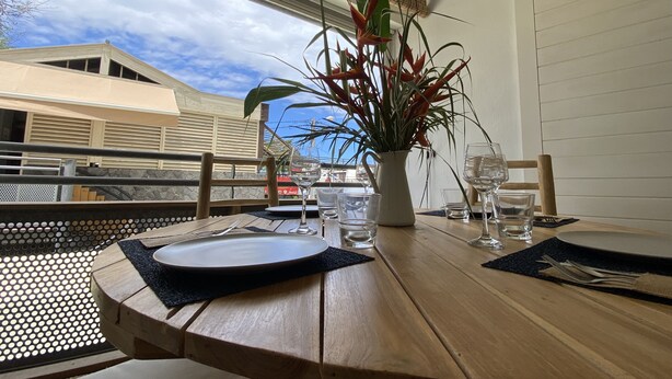 Una mesa de comedor dispuesta con platos, cubiertos y una planta en maceta.