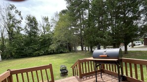 Une terrasse en bois avec un barbecue et une petite table.