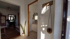 A room with a tiled floor, a wooden door, a wall-mounted mirror, and a potted plant. - Simple beach house, 6 minute walk to the beach, mountain views (Setúbal)