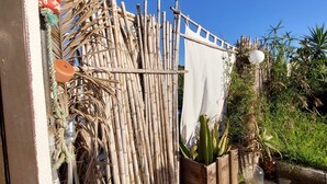 A rustic outdoor area with a bamboo fence, a small water feature, and various plants. - Simple beach house, 6 minute walk to the beach, mountain views (Setúbal)
