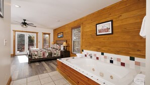 Une chambre spacieuse dotée d’une grande tête de lit en bois, d’un lit double, d’un dressing et d’une grande baignoire.