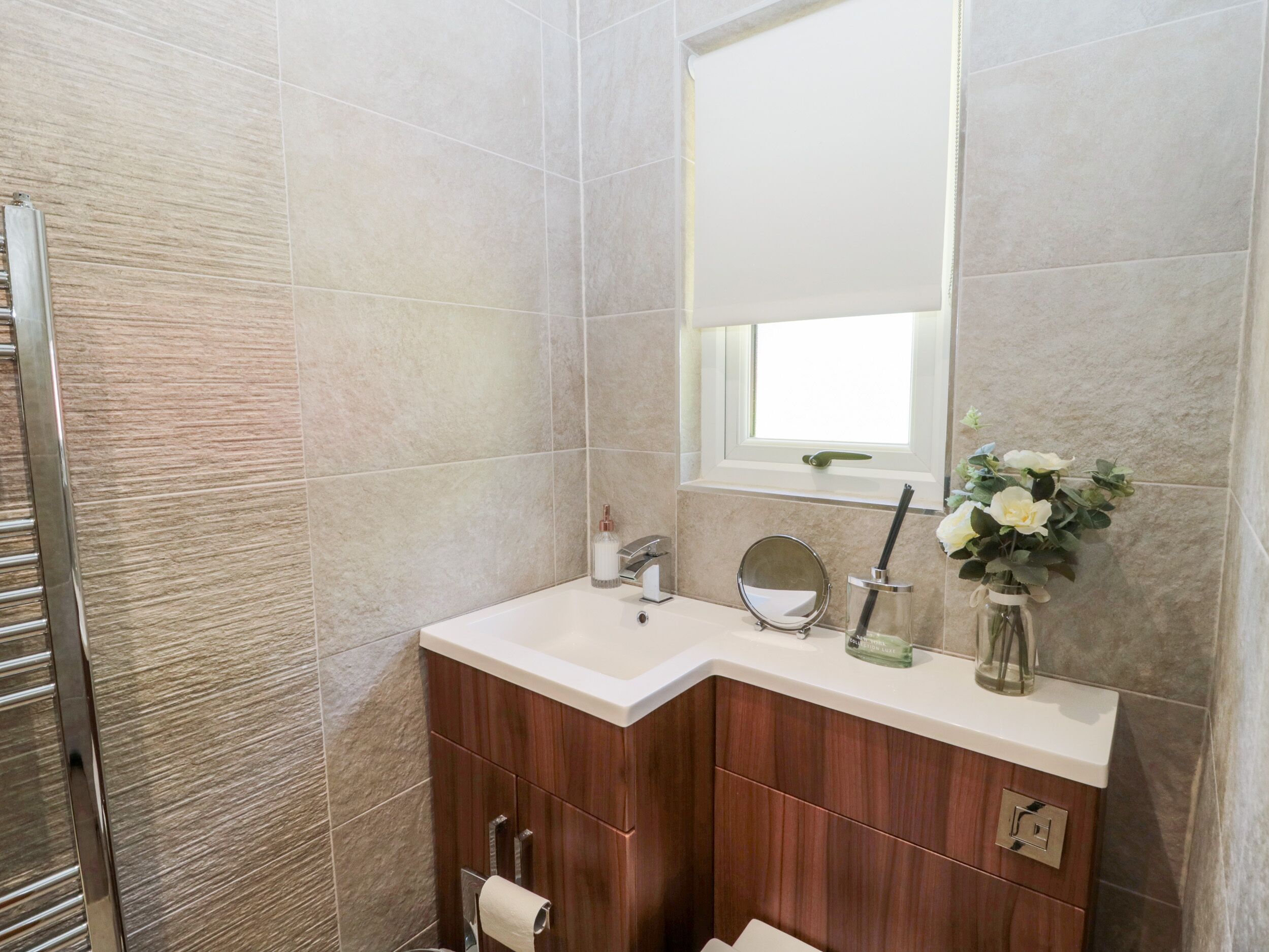 Un baño con tocador de madera, un espejo, un lavamanos y una ventana.