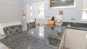A modern kitchen with a granite countertop, a tufted chair, and a sign for Moët & Chandon champagne. - Lodge 32 (Newcastle-upon-Tyne)