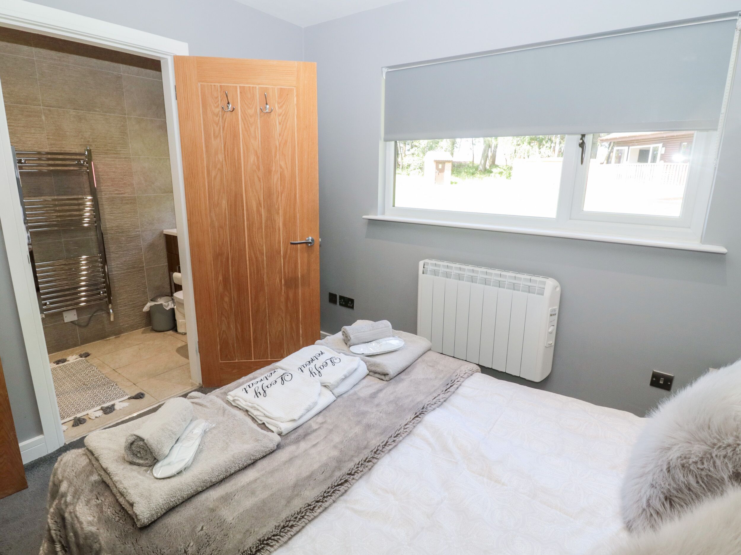 A bedroom with a bed, a radiator, a window, and a wooden door.