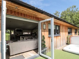 Una cabaña de madera con una puerta corrediza abierta que muestra una sala de estar con un sofá y una mesa de comedor.