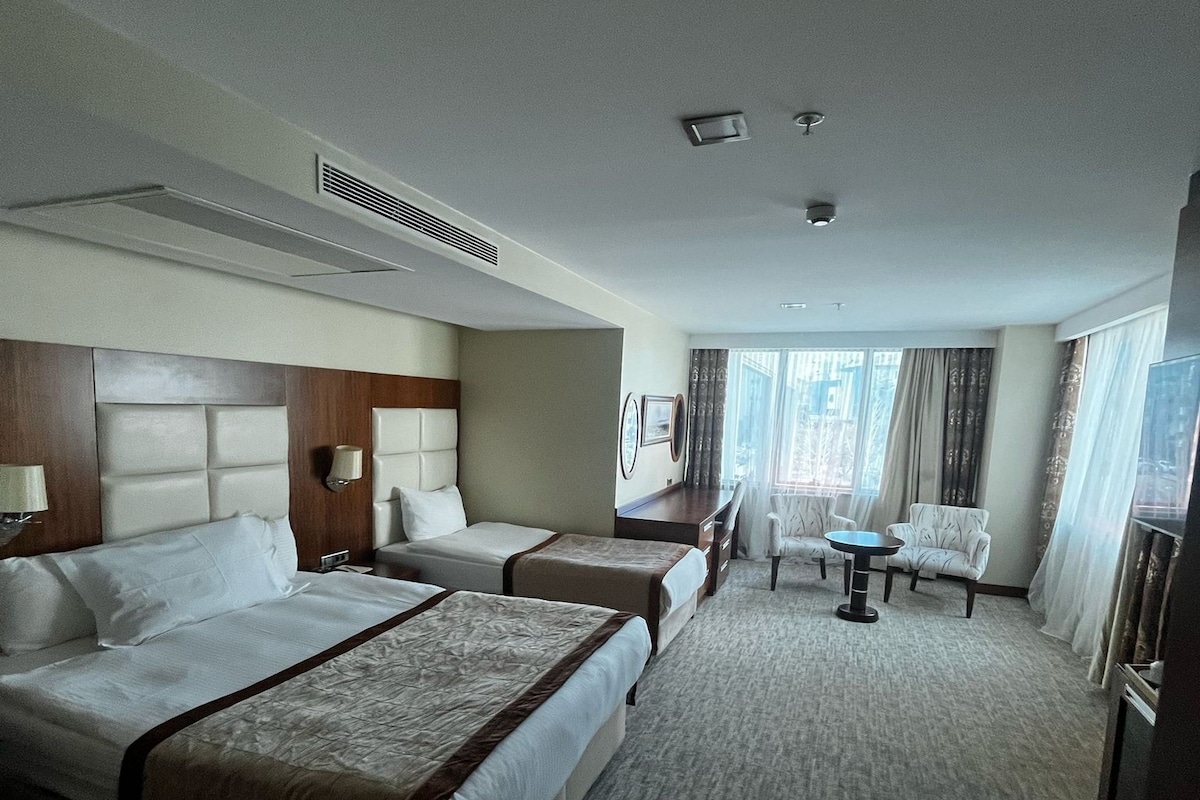 Habitación de hotel con dos camas, un escritorio, una silla y un televisor.