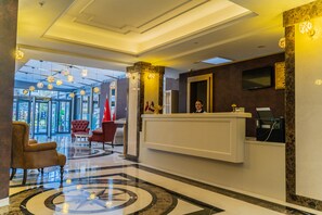 A hotel reception area with a marble floor, a reception desk, and a large window offering a view of the outdoors. - Akman Premium Hotel (Ankara)