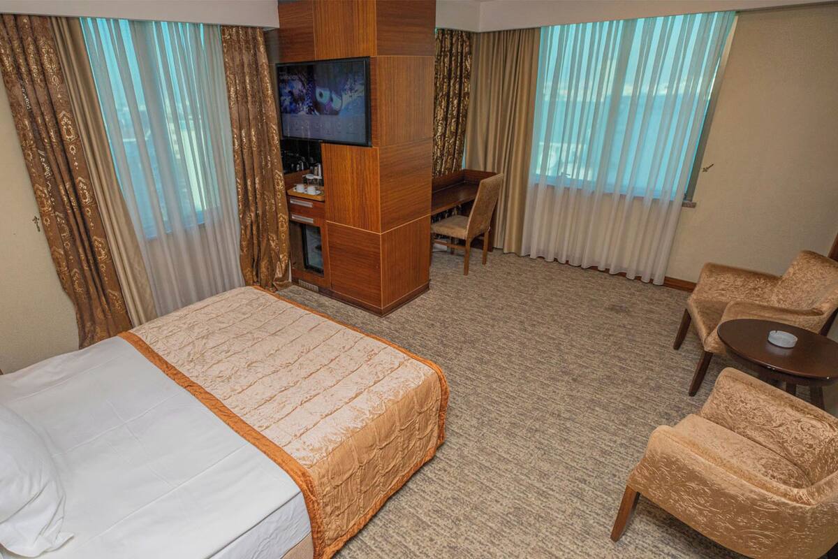 Habitación de hotel con una cama grande, un escritorio, un televisor y dos sillas.