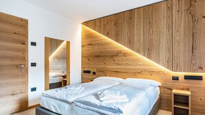 Une chambre à coucher moderne avec un grand lit, une tête de lit en bois, des tables de chevet et une armoire intégrée.