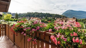 Un balcon avec une balustrade en bois, une vue sur des maisons et une montagne en arrière-plan.