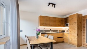 Une cuisine moderne avec des meubles en bois, une table à manger avec des chaises et une petite plante en pot.