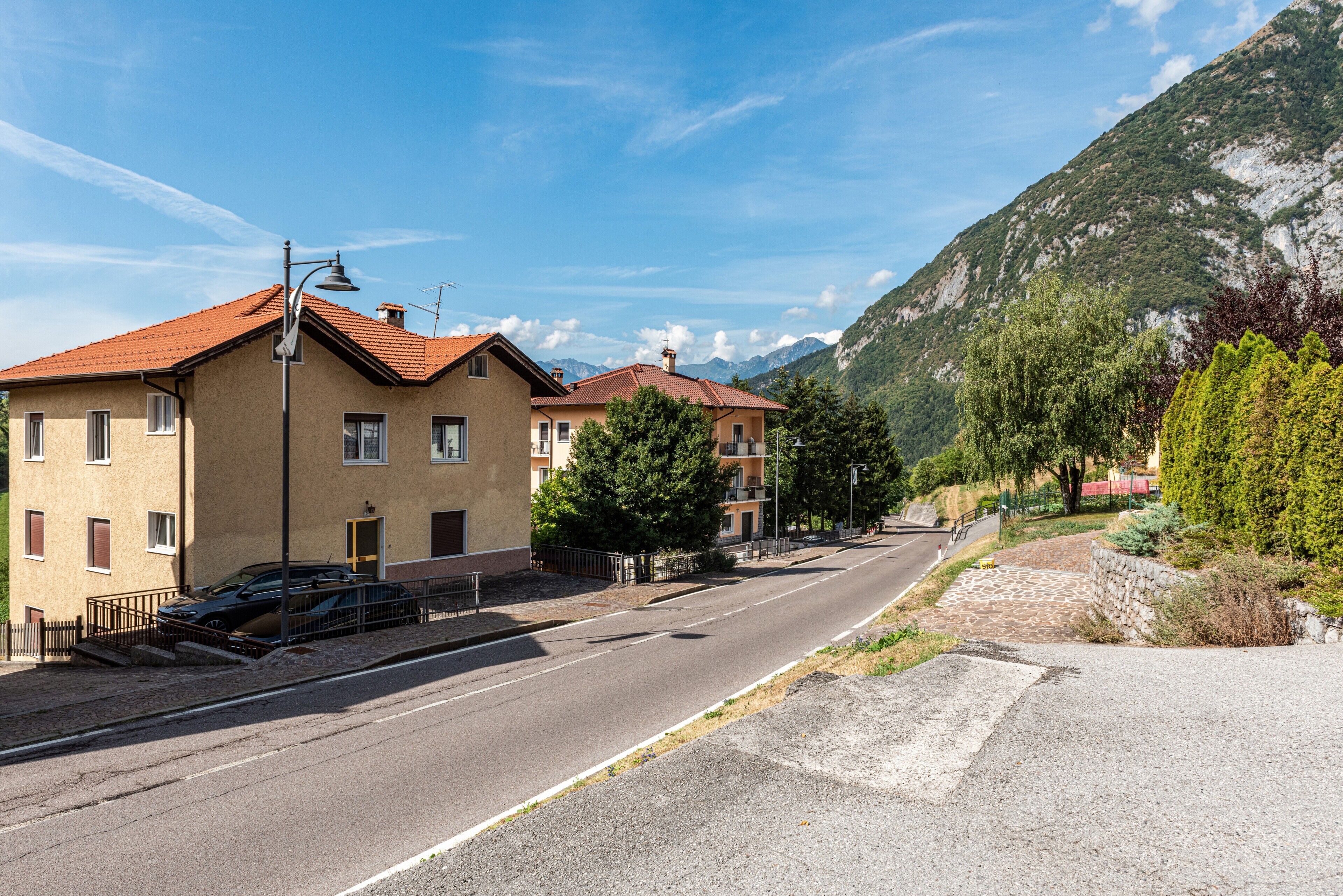 Une rue bordée d’immeubles, un ciel dégagé et des montagnes en arrière-plan.