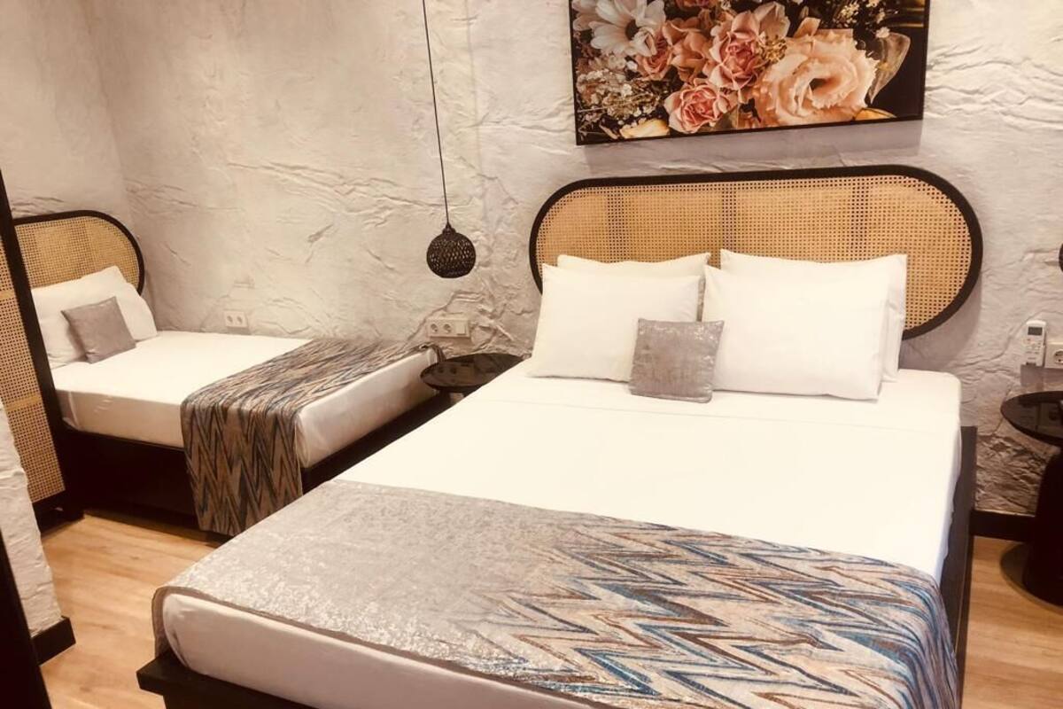 A bedroom with two beds, a large painting, and a hanging light fixture.