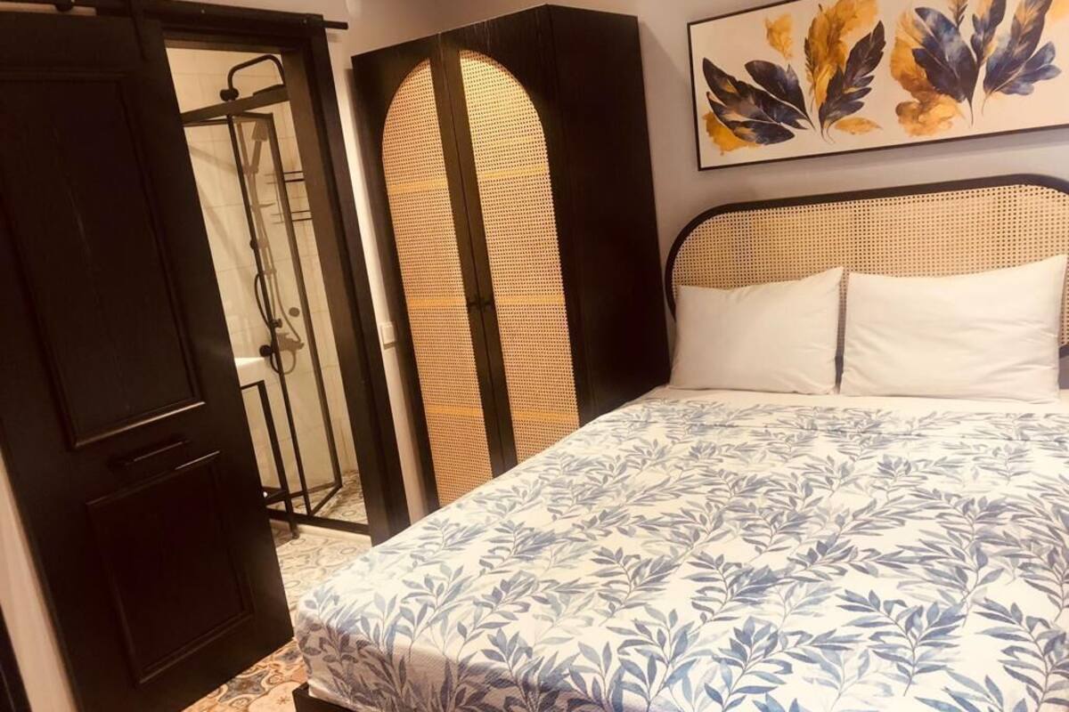 A bedroom with a bed, a wardrobe, and a shower area.