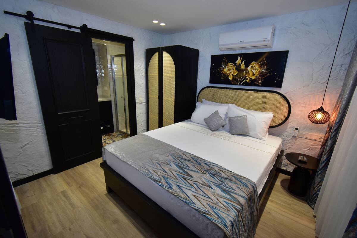 A modern bedroom with a bed, a wardrobe, a bedside table, and a wall-mounted air conditioner.
