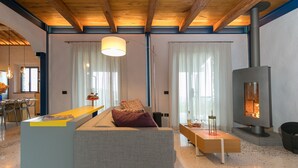 Una sala de estar moderna con un sofá, un banco de madera, una chimenea y un comedor con sillas y una mesa.