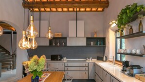 Una cocina moderna con armarios de madera, una mesa de comedor con sillas, lámparas colgantes y una ventana con vistas.
