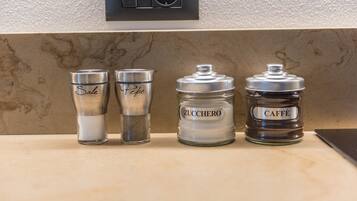 Four glass containers on a kitchen counter with labels 'Sale,' 'Pepe,' 'Zucchero,' and 'Caffè.'