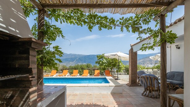 A pool area with lounge chairs, a barbecue, and a view of mountains. - Villa 'Liviana' with Mountain View, Pool & Wi-Fi (Cómpeta)