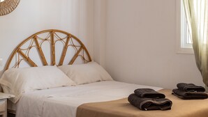 A bed with a woven headboard, white bedding, and two rolled towels on the bed. - Villa 'Liviana' with Mountain View, Pool & Wi-Fi (Cómpeta)