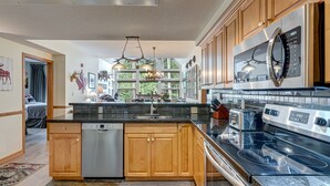 A modern kitchen with wooden cabinets, a stainless steel range, and a dishwasher. - Call to the Wild in Canmore! (Canmore)