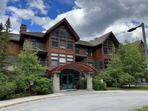 A multi-story hotel with a prominent entrance, large windows, and a stone facade. - Call to the Wild in Canmore! (Canmore)