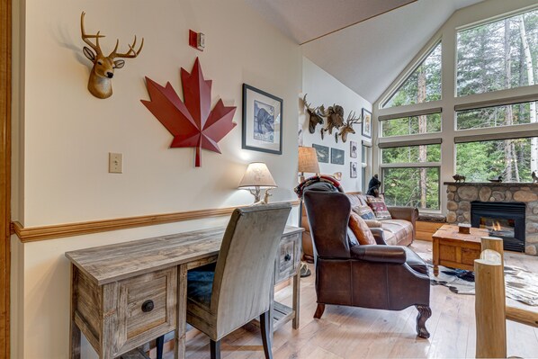 A cozy living room with a fireplace, a desk, and a leather armchair.