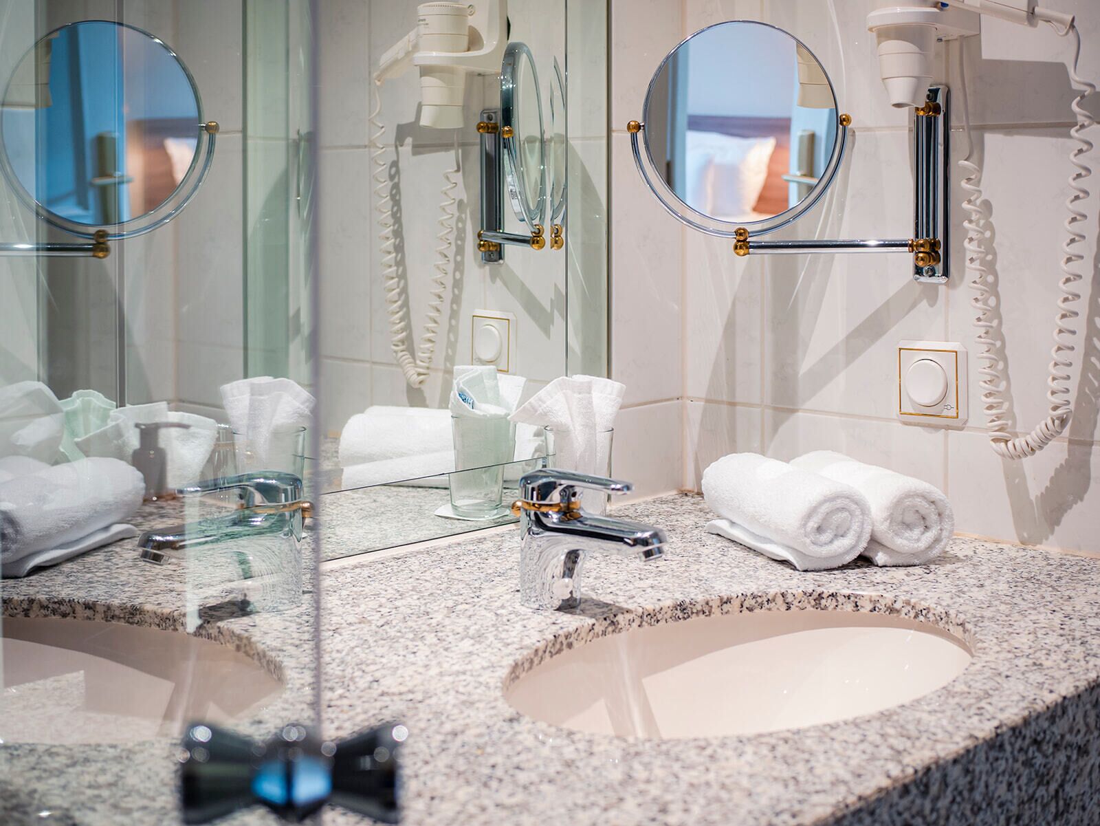 A bathroom with two sinks, mirrors, and a towel rack.