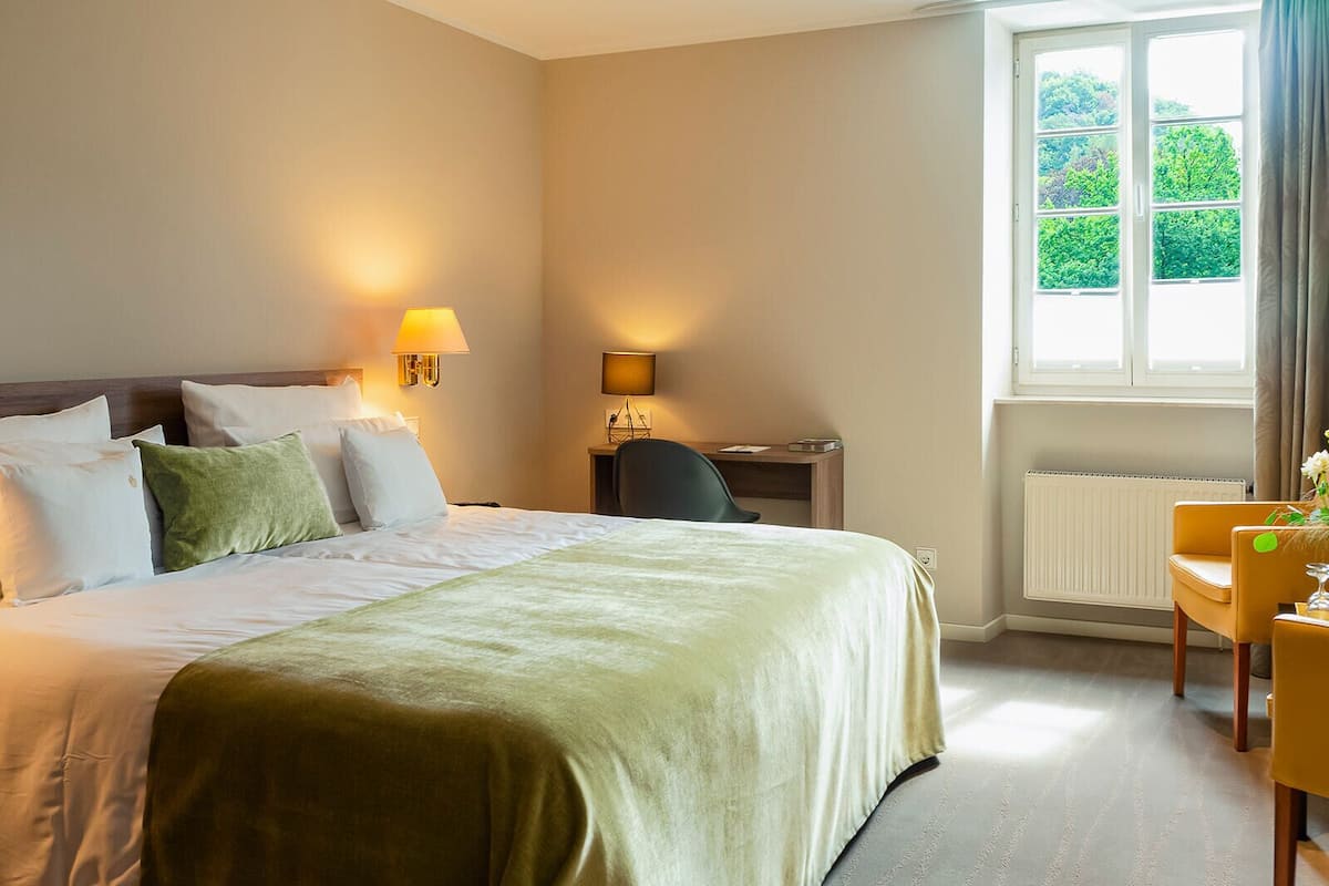 Een hotelkamer met een groot bed, twee bedlampen, een bureau en een stoel.