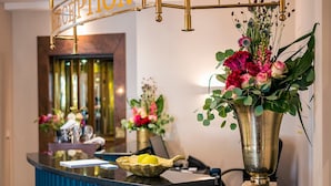 A reception desk with a gold sign, a vase of flowers, and a fruit bowl.
