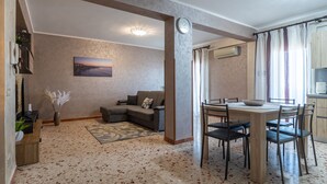 Un salon avec un canapé, une table à manger et des chaises, une horloge et un tableau accroché au mur.