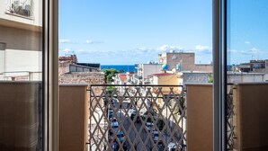 Un balcon offrant une vue sur le paysage urbain, avec des bâtiments et un ciel dégagé.