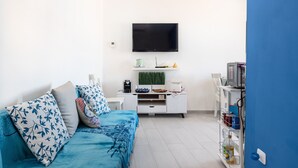 A modern living room with a sofa, TV, white cabinet, and a blue wall. - Apartment Le Primule, pet-friendly, with sea view and balcony (Agrigento)