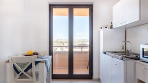 A compact kitchen with a dining area, a refrigerator, and a view through a sliding door. - Apartment Le Primule, pet-friendly, with sea view and balcony (Agrigento)