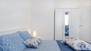 A bedroom with a bed, pillows, a nightstand, and a wardrobe. - Apartment Le Primule, pet-friendly, with sea view and balcony (Agrigento)