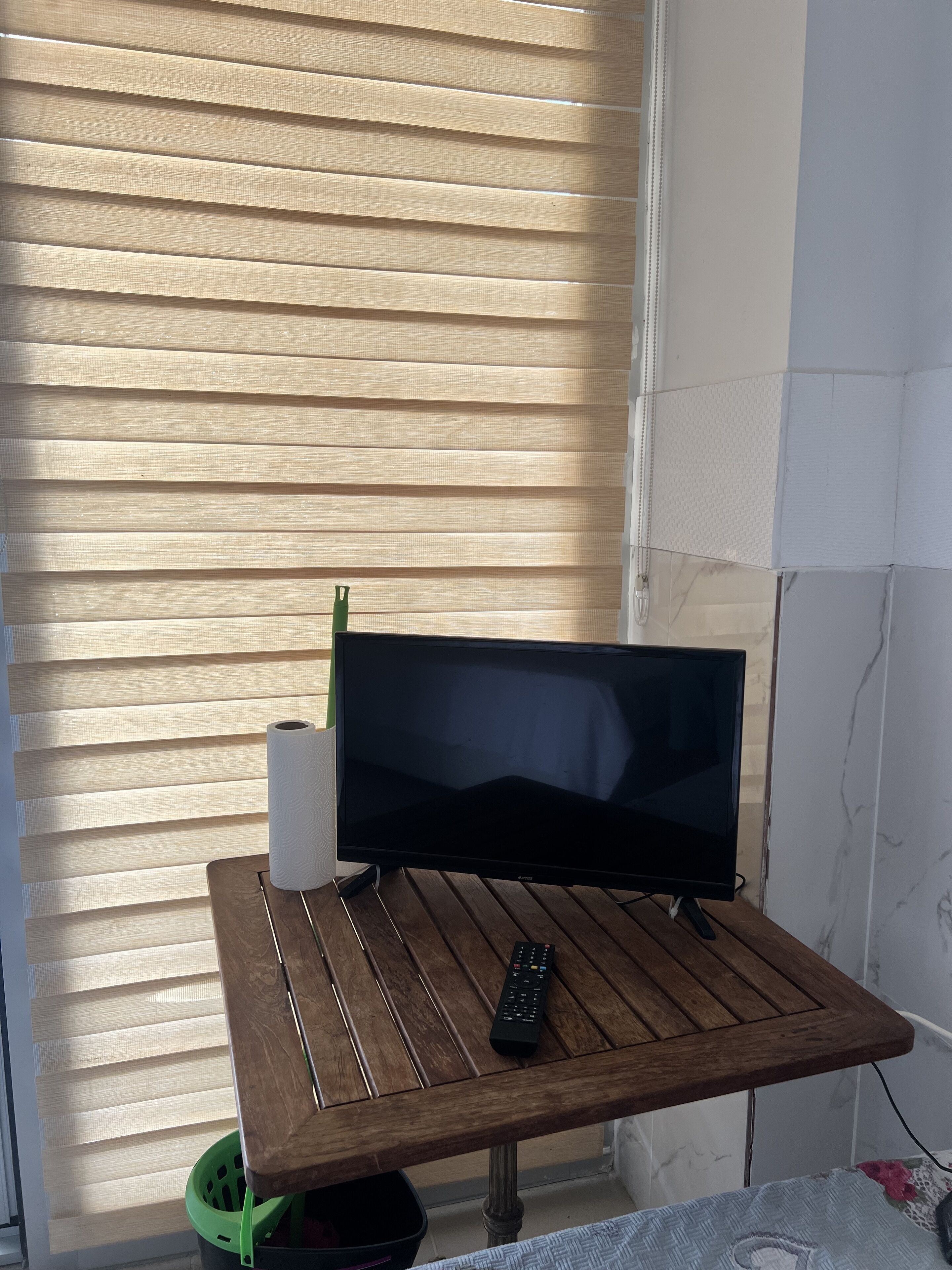 Un televisor sobre una mesa de madera con un control remoto y un rollo de toallas de papel.