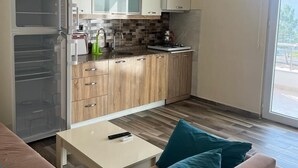 A modern kitchen with white cabinets, a microwave, and a stove. There is a sliding glass door leading to an outdoor area. - Cirpan Apart Otel (Enez)