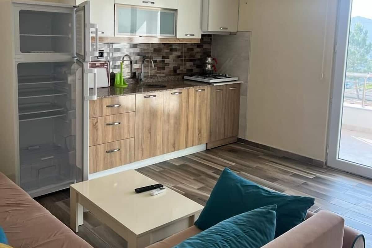 Cocina moderna con armarios blancos, microondas y estufa. Hay una puerta corrediza de vidrio que da a un espacio al aire libre.