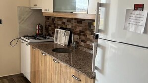 A compact kitchen with a refrigerator, microwave, and stove. - Cirpan Apart Otel (Enez)
