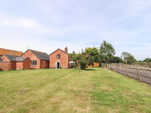 A brick farmhouse with a well-maintained lawn and a wooden fence. - Hill Farm (Nantwich)