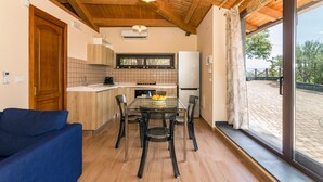 A modern kitchen with wooden ceiling, a dining table with chairs, a sofa, and a large window with a view. - Holiday Home Casetta delle Rose with A/C and Wi-Fi (Viagrande)