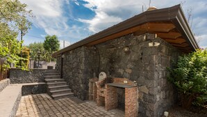A stone building with a brick barbecue area, a staircase leading up, and a paved patio. - Holiday Home Casetta delle Rose with A/C and Wi-Fi (Viagrande)