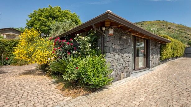 A stone building with a sloped roof, a paved driveway, and a variety of flowering plants. - Holiday Home Casetta delle Rose with A/C and Wi-Fi (Viagrande)