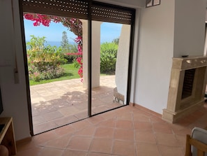Una habitació amb una porta corredissa de vidre que dona a un pati amb vistes a vegetació i un paisatge llunyà.