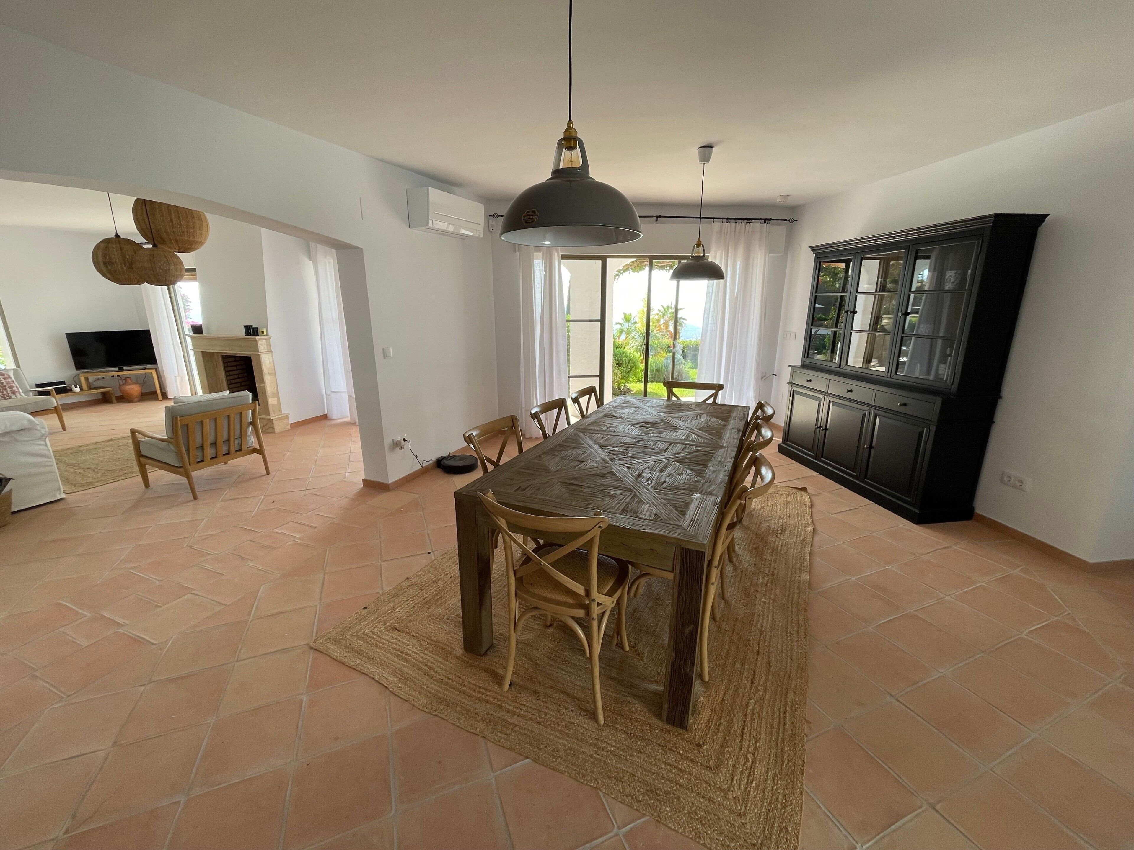 Amplia sala de estar con una mesa de comedor, sillas, televisor y una zona de cocina.