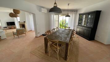 Amplia sala de estar con una mesa de comedor, sillas, televisor y una zona de cocina.