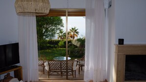A room with a TV, a fireplace, and a view of an outdoor patio with chairs and a table.
